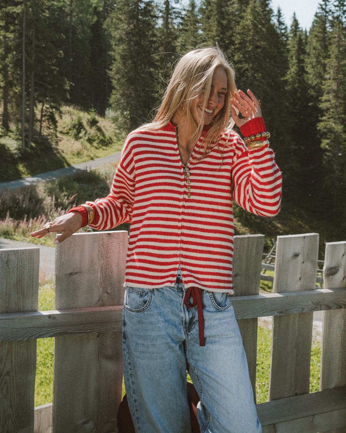 Model draagt een rood met wit gestreept vest met rits